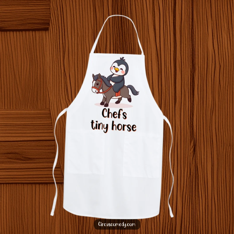 Funny penguin humorously attempting to ride a small horse, featured on a practical apron for kitchen fun and protection.