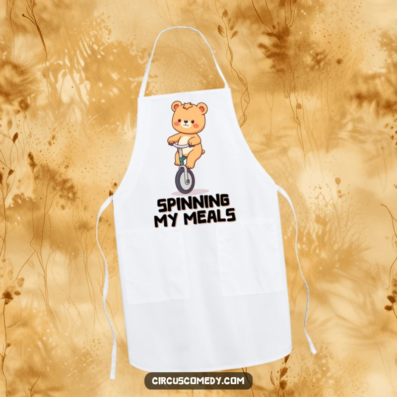 Funny apron showing a playful bear riding a unicycle while holding cooking utensils with a cheerful expression.